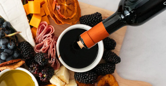 An overhead photo of balsamic vinegar being poured onto a charcuterie board.