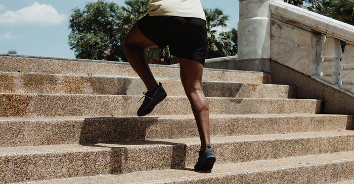 Person running up outdoor stone steps, view from behind showing legs mid-stride