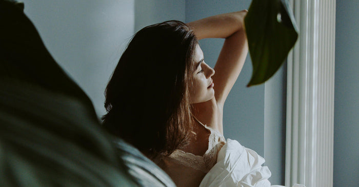Woman stretching, waking up well rested due to supported circadian rhythm.