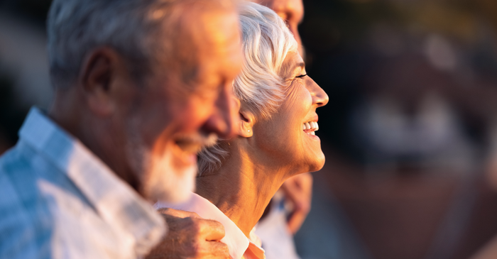 Happy elderly couple smiling outdoors in sunlight.