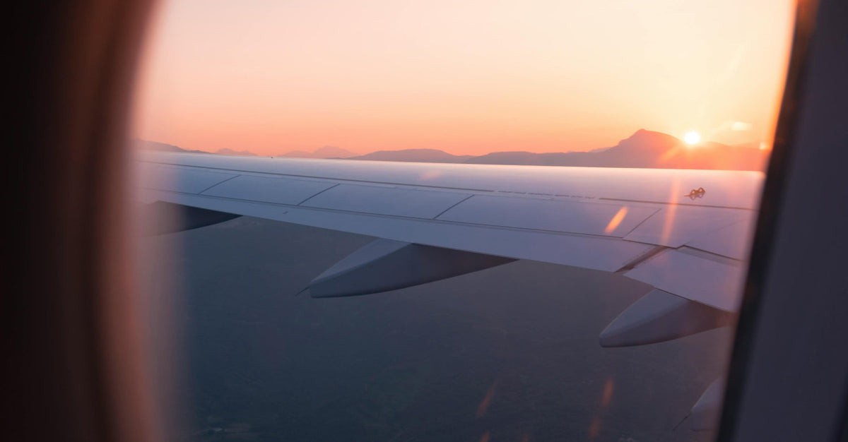 View from an airplane window at sunrise or sunset, symbolizing long-distance travel and time zone changes associated with jet lag.