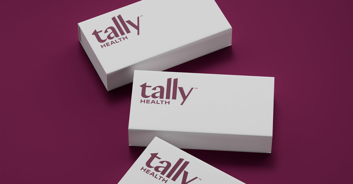 Three white Tally Health branded boxes with the Tally Health logo, arranged diagonally on a dark maroon background.
