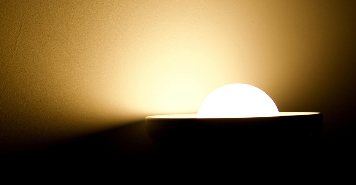 Soft warm light from a lamp illuminating a wall, creating a calming indoor atmosphere.