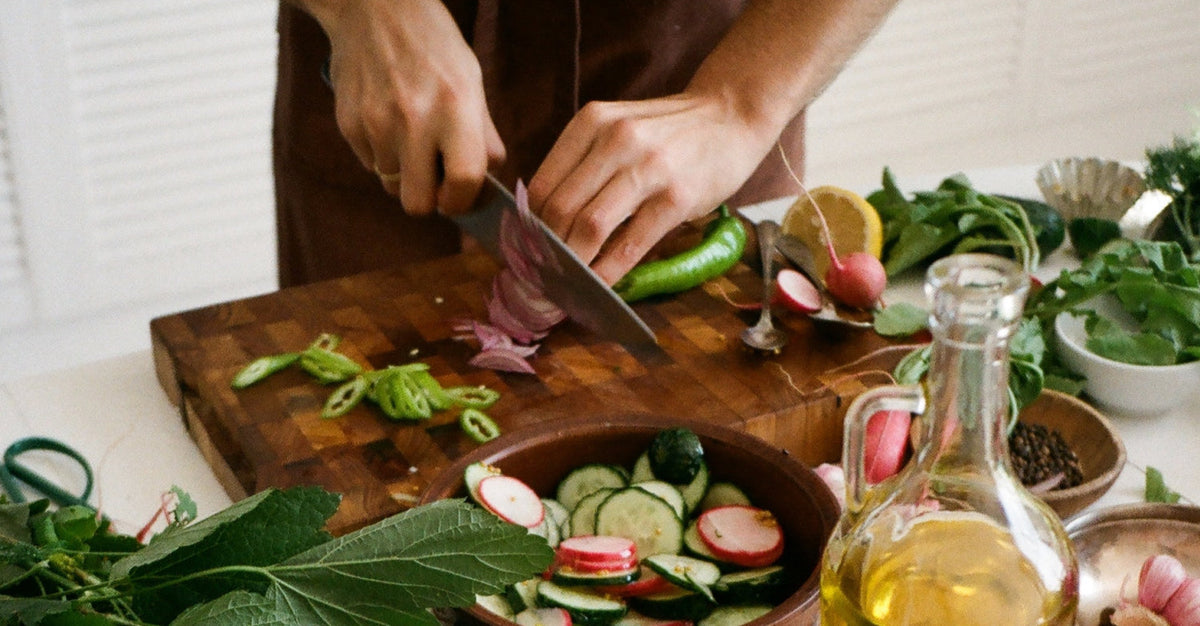 A close up of hands chopping various vegetables and olive oil - a core part of a mediterranean diet.