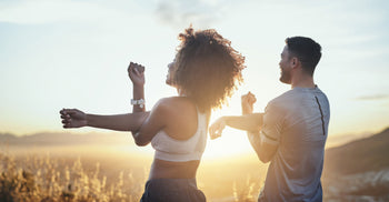 Two people stretching and smiling outdoors at sunrise, emphasizing movement and metabolic health.