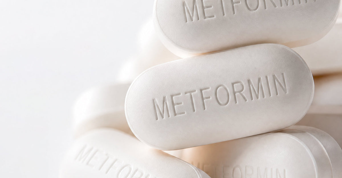 Close-up of white oblong metformin pills stacked together, each embossed with 