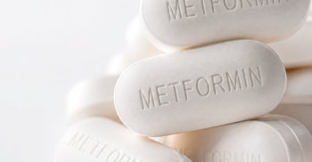 Close-up of white oblong metformin pills stacked together, each embossed with 