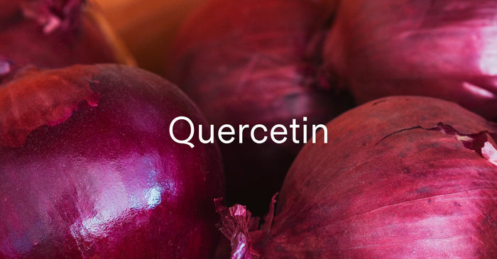 A close-up shot of several red onions with the word 