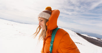 Person wearing a winter jacket and knit hat outdoors in snowy conditions, highlighting cold-weather environmental exposure.