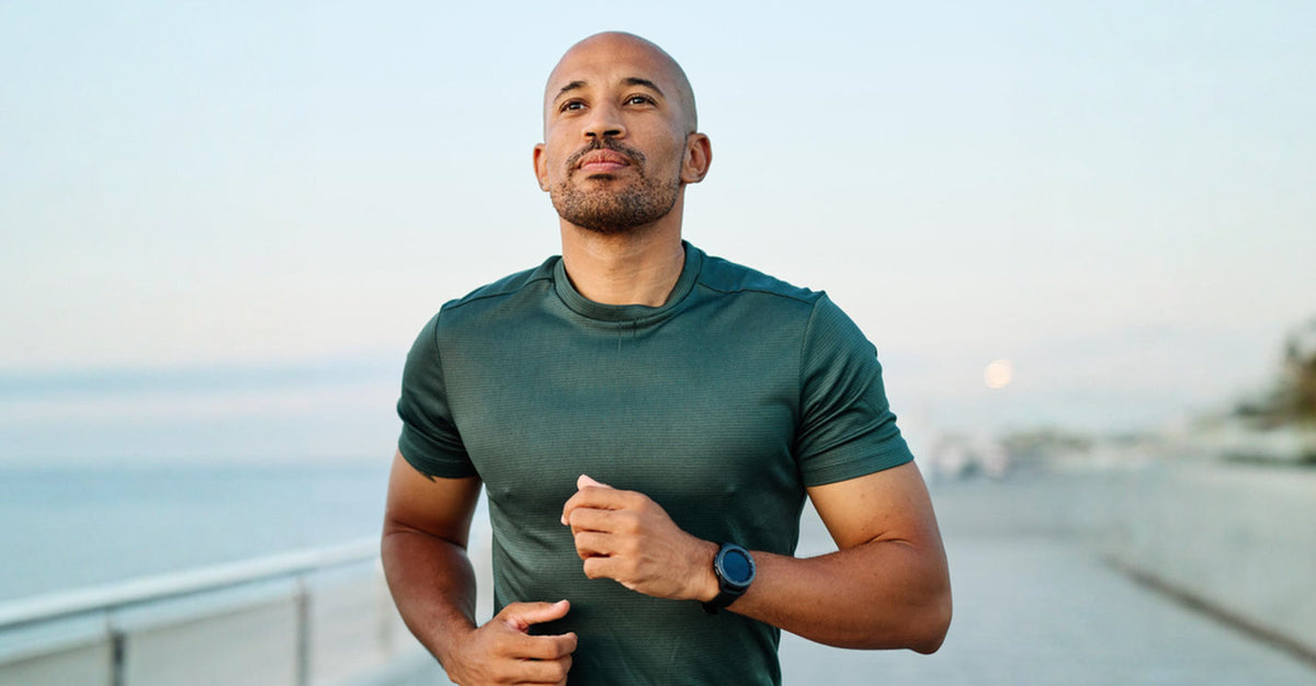 Man jogging outdoors at sunrise wearing a heart rate monitor, training in Zone 2 cardio